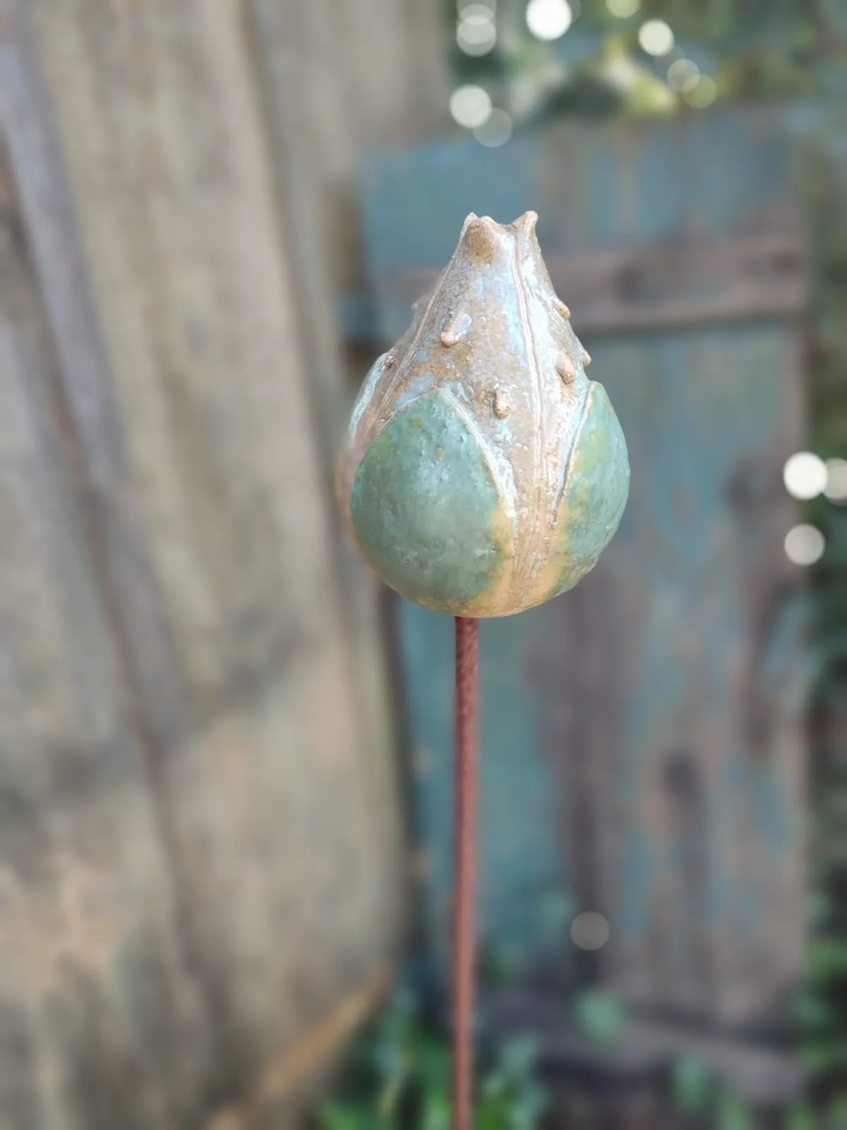 Detailaufnahme einer keramischen Mohnkapsel im Garten